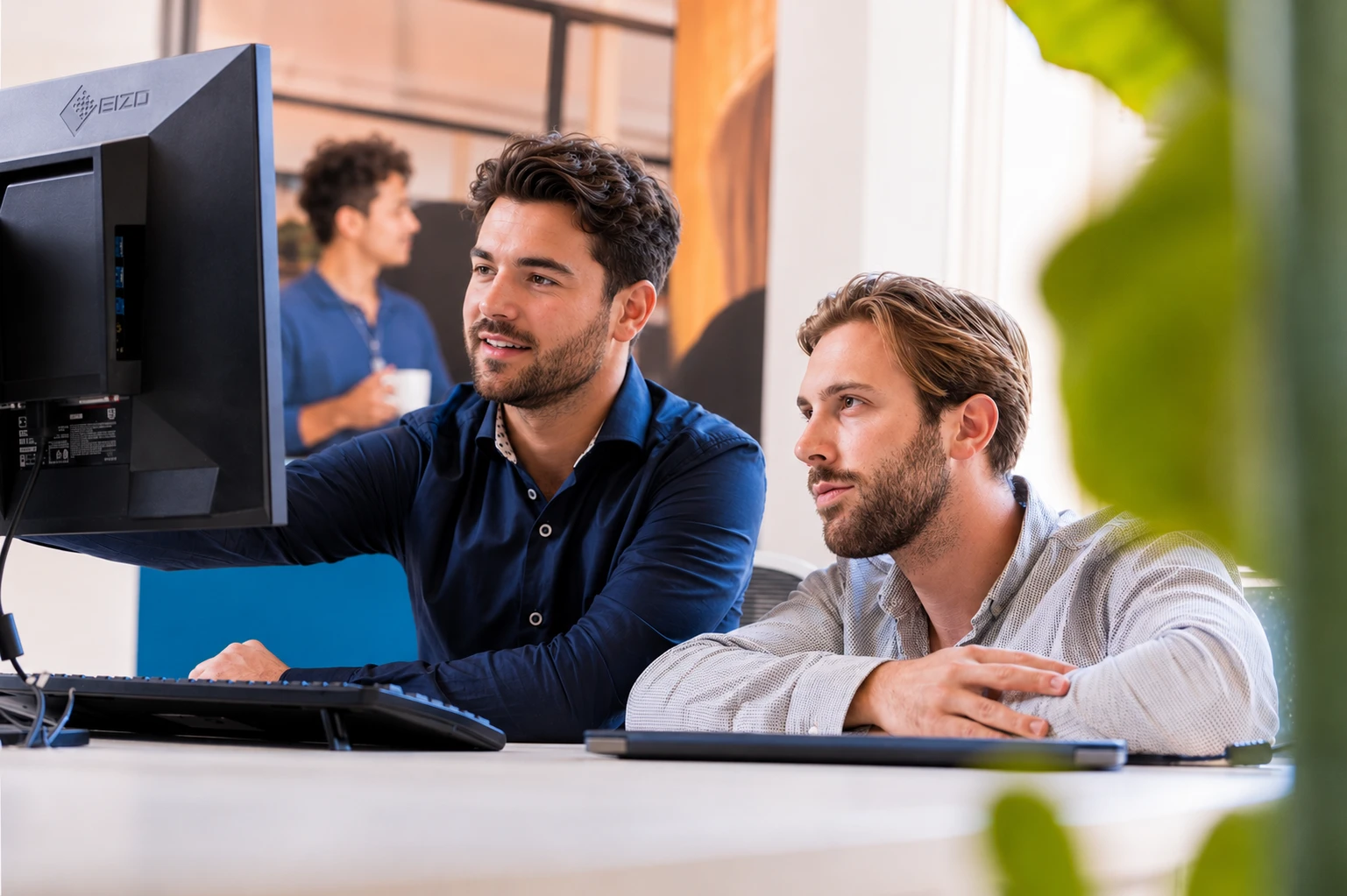 Sam de Vries (rechts) aan het werk achter de computer
